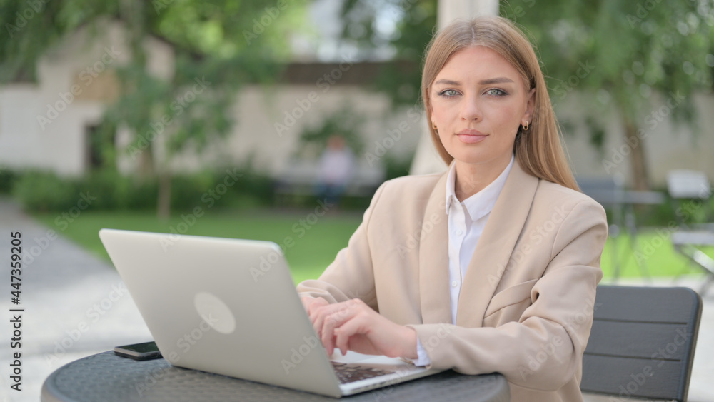 Businesswoman with Laptop Looking at Camera in Outdoor Cafe Businesswoman with Laptop Looking at Camera in Outdoor Cafe
