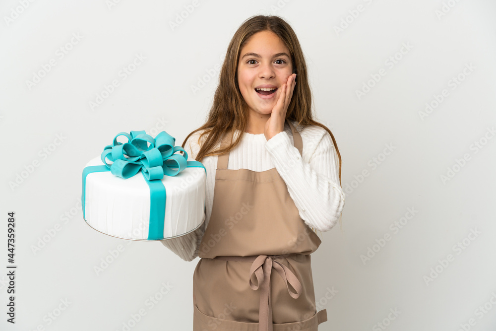 Little girl holding a big cake over isolated white background with surprise and shocked facial expression Little girl holding a big cake over isolated white background with surprise and shocked facial expression
