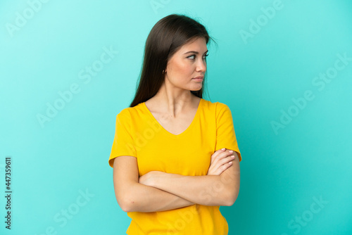 Young caucasian woman isolated on blue background keeping the arms crossed