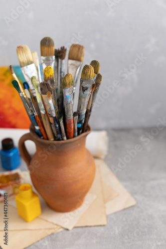 Paint brush in clay jug and art painter tool on table background texture. Paintbrush for painting