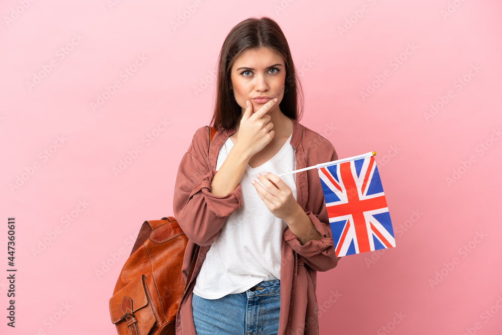 Young caucasian woman holding an United Kingdom flag isolated on pink background thinking Young caucasian woman holding an United Kingdom flag isolated on pink background thinking