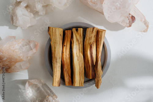 Palo Santo sticks on a concrete plate and natural crystals, beautifully illuminated by sunlight. Set of incense for fumigation. Top view. Organic sacred tree incense from Latin America. photo