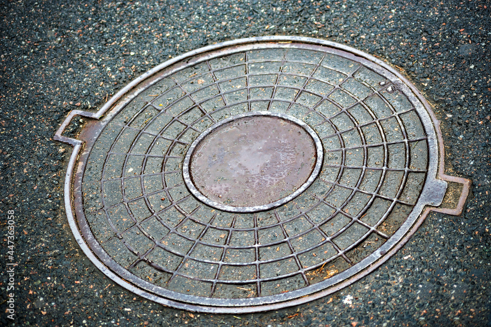 Metal covers of sewer manholes on city roads close-up.