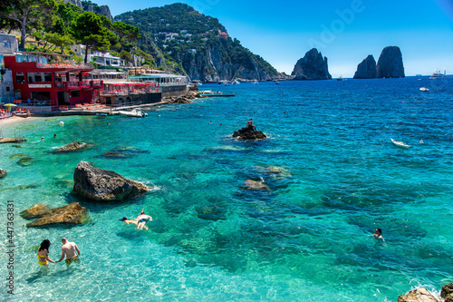 Foto CAPRI, ITALY - JUNE 15, 2021: Tourists visit Marina Piccola Beach with a view on famous Faraglioni