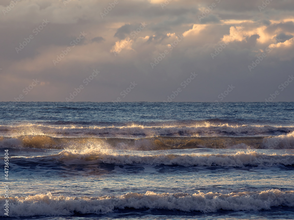 The waves of the Baltic Sea are illuminated by the setting sun.