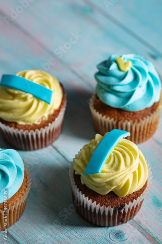Yellow and blue cute and yummy homemade muffins cake on a wooden board surface