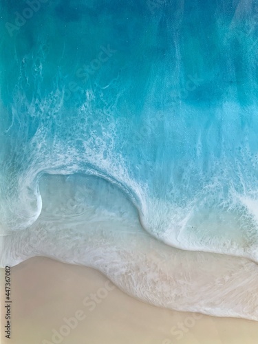 Top view on sea wave with white foam and light beige sand. drawing with epoxy resin. Close-up of deep rich blue, azure, turquoise color of water, shore. Trendy painting, summer sunny beach, seascape 