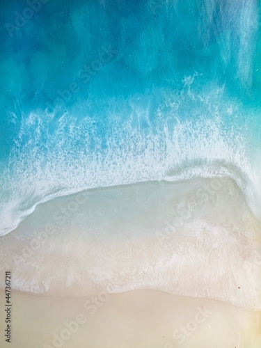 Top view on sea wave with white foam and light beige sand. drawing with epoxy resin. Close-up of deep rich blue, azure, turquoise color of water, shore. Trendy painting, summer sunny beach, seascape 