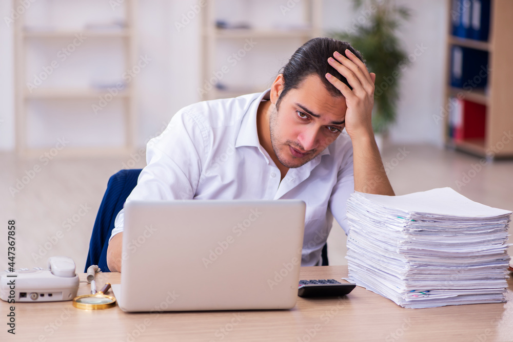 Young businessman employee unhappy with excessive work in the office Young businessman employee unhappy with excessive work in the office