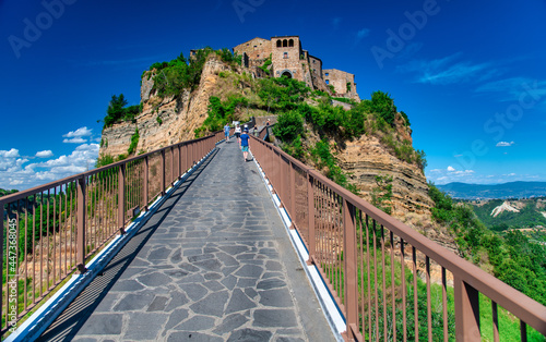 CIVITA DI BAGNOREGIO, ITALY - JULY 2, 2021: Tourists walk along major bridge to reach medieval town.