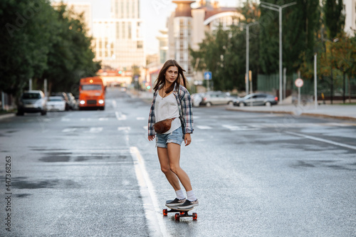 Pretty woman riding on a skateboard on an empty city road early in morning