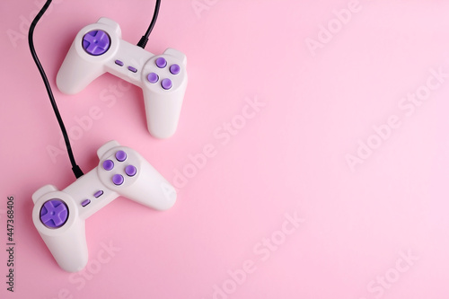 Two video game joysticks on pink background, closeup. Game addicted concept.