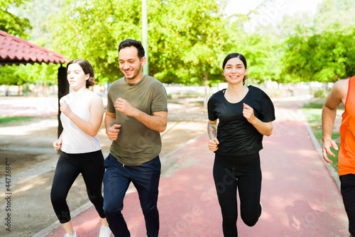 Cheerful friends jogging at the park track