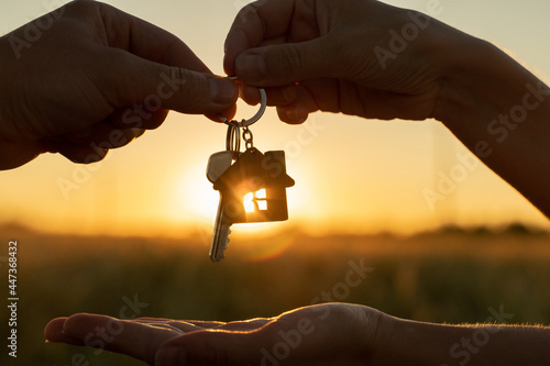Photo Close-up female gives a man the key to a new house on the background of a beautiful sunset