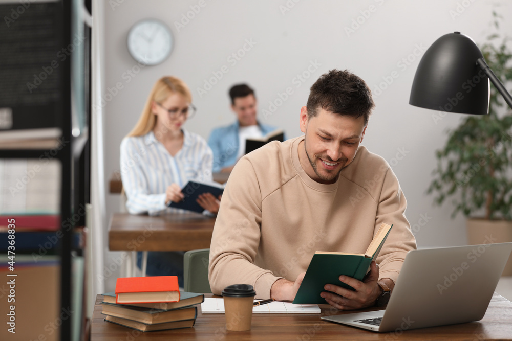Man reading book at table in library