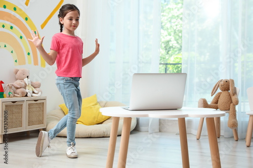 Cute little girl taking online dance class at home photo