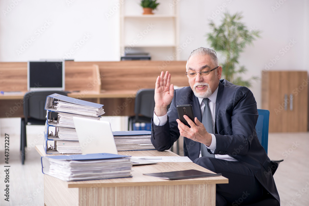 Aged male employee sitting at workplace Aged male employee sitting at workplace
