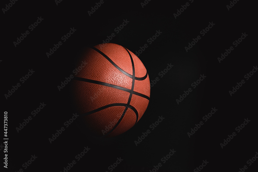 Basketball on black background in the dark with advertising space