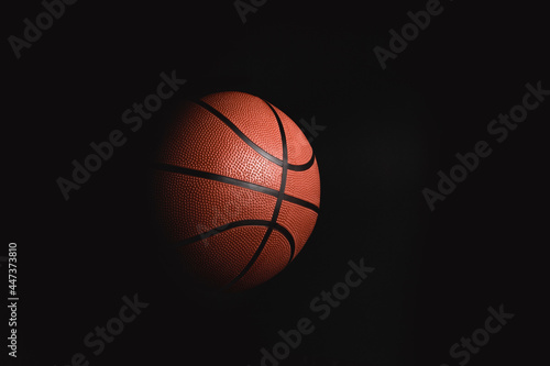 Basketball on black background in the dark with advertising space