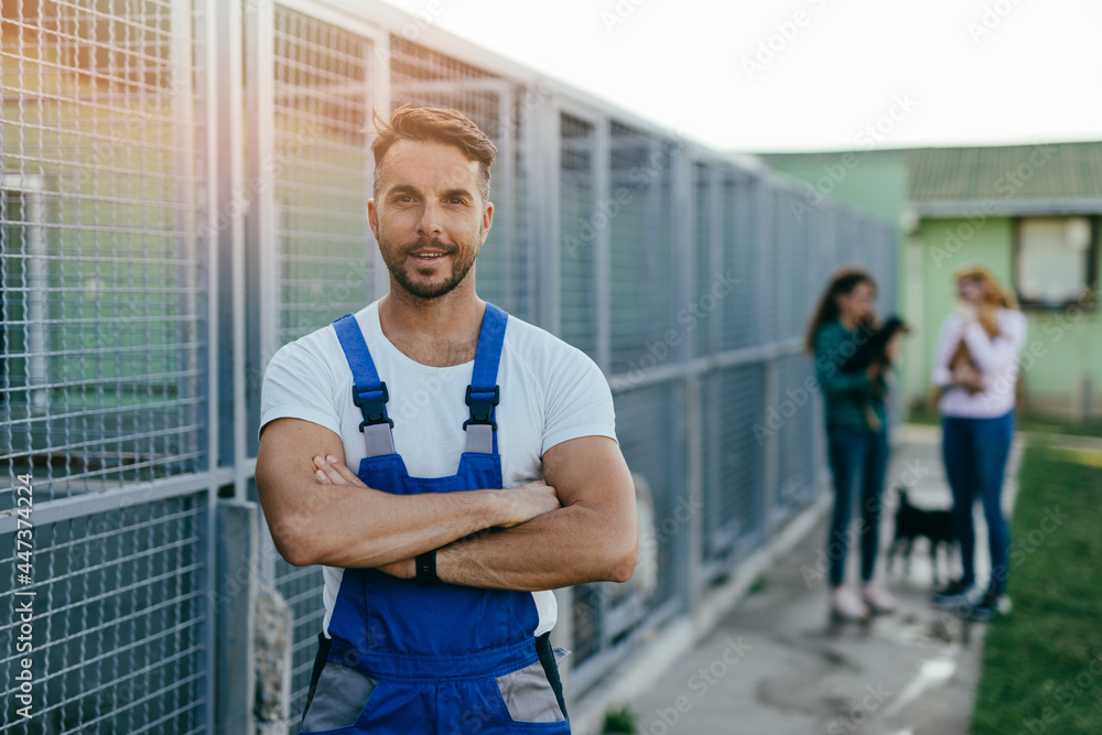 Young handsome adult male worker in animal shelter holding adorable dogs.. Young handsome adult male worker in animal shelter holding adorable dogs..