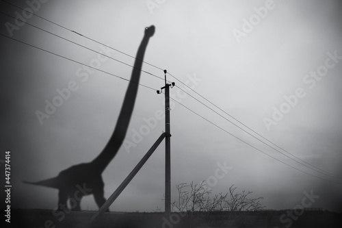 Obraz na plátně Silhouette of huge brontosaurus in dark fog and pillar with electric wires, gloo