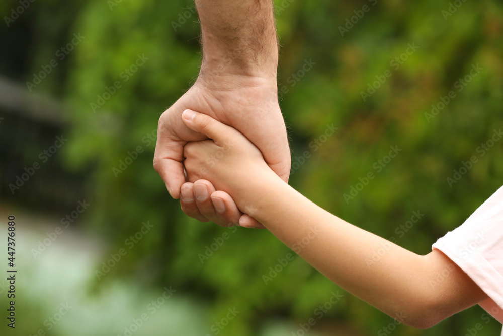 Man and child holding hands outdoors, closeup Man and child holding hands outdoors, closeup