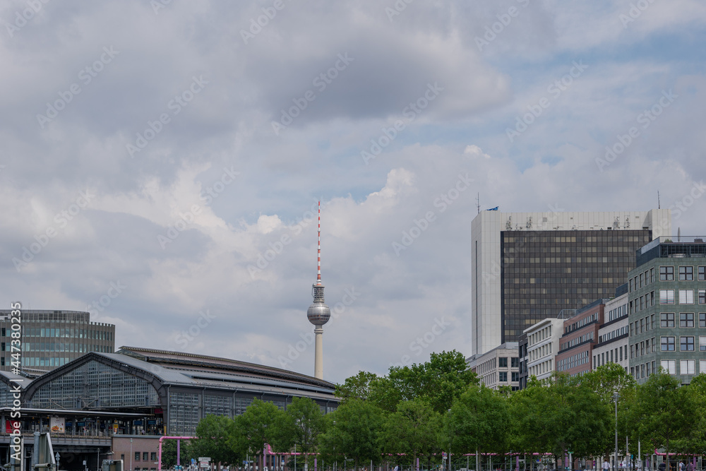 View of Berlin Friedrichstrasse S-bahn station and background of Fernsehturm against cloudy sky in Berlin, Germany.