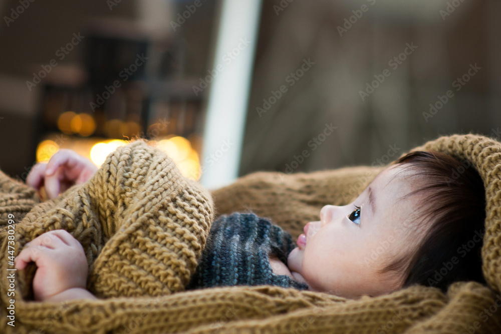 The baby wrapped in a blanket is looking up. The baby wrapped in a blanket is looking up.