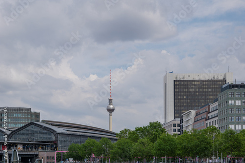 View of Berlin Friedrichstrasse S-bahn station and background of Fernsehturm against cloudy sky in Berlin, Germany.