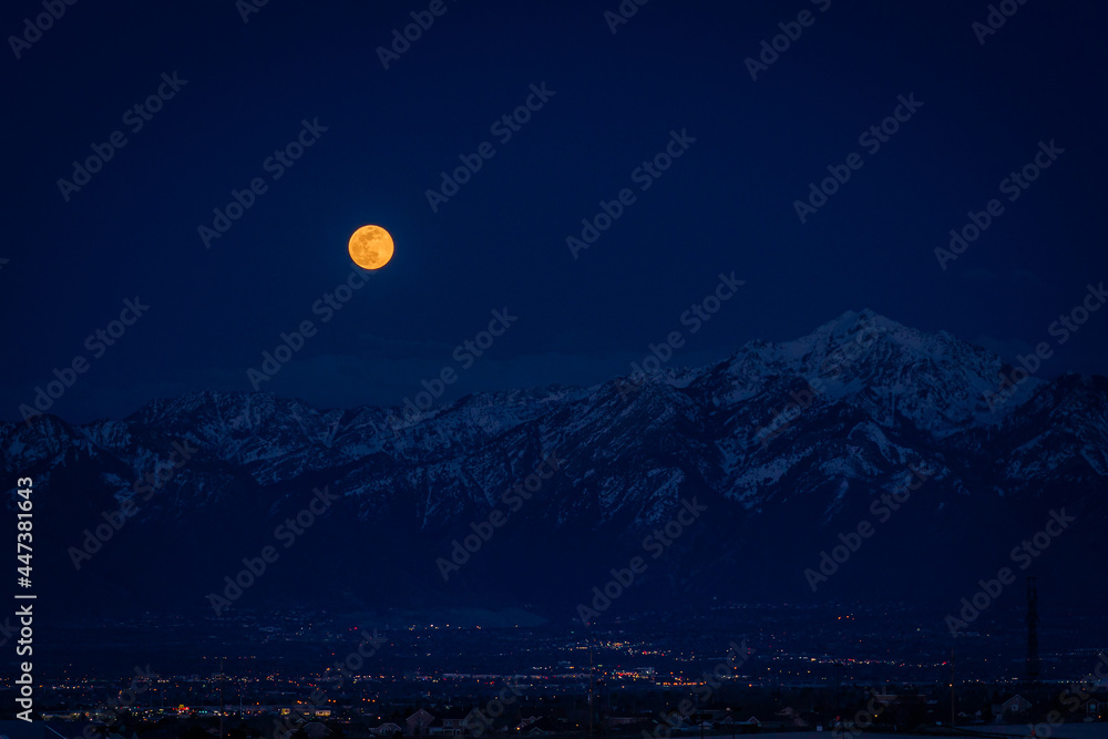 Moonrise over the Wasatch mountain range with night city lights below Moonrise over the Wasatch mountain range with night city lights below