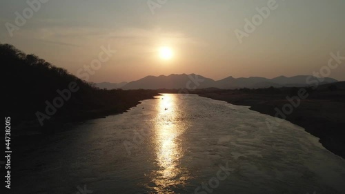men sail on the river at sunset