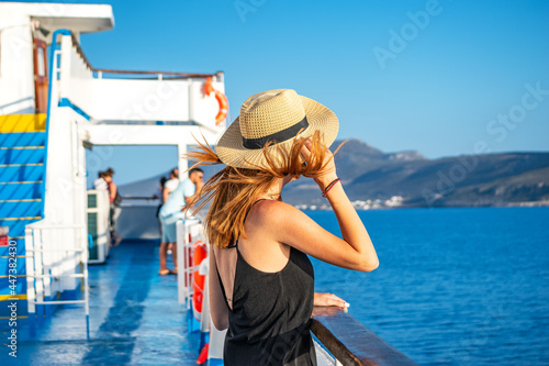 Elegant woman with casual dress and hat on a ferry boat on the Aegean sea, Cyclades, Greece