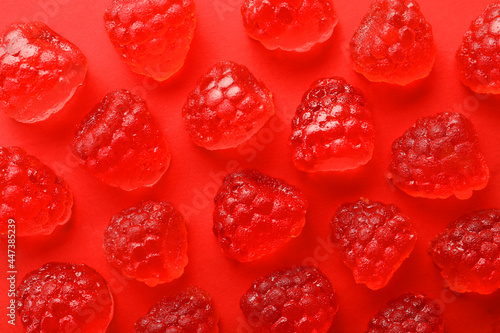 Delicious gummy raspberry candies on red background, flat lay