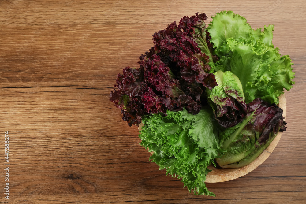 Different sorts of lettuce on wooden table, top view. Space for text Different sorts of lettuce on wooden table, top view. Space for text