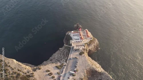 Aerial pull out view of Saint Vincent cape lighthouse located on top of natural formation rugged cliff, Sagres.