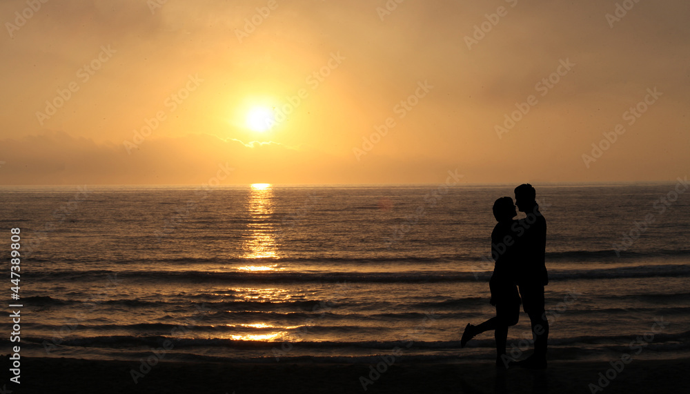 Lovers on the beach at sunset. happy Couple Kissing and hugging in Front Of Sun and sea waves. Romantic Lover Concept  