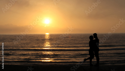 Lovers on the beach at sunset. happy Couple Kissing and hugging in Front Of Sun and sea waves. Romantic Lover Concept  