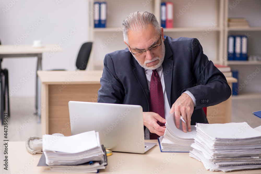 Aged male employee and too much work at workplace Aged male employee and too much work at workplace