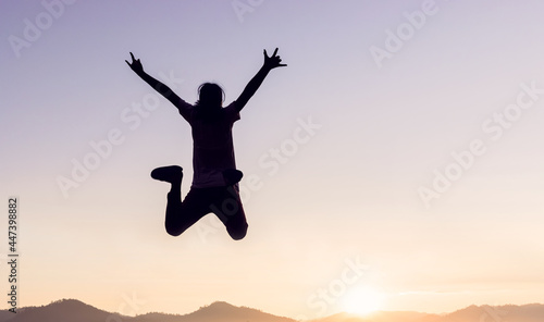 Silhouette of happy people jumping playing on mountain at sunset or sunrise