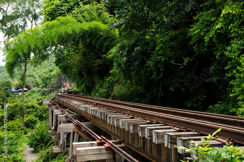 Train railway track between hellfire pass mountain and Si Sawat or Khwae Kwai river with forest jungle wildness in Sai Yok National Park for travel visit at Tham krasae cave in Kanchanaburi, Thailand photo