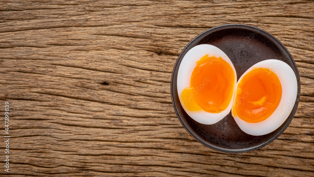 superb runny yolk boiled egg in ceramic plate on rustic natural wood texture background, top view superb runny yolk boiled egg in ceramic plate on rustic natural wood texture background, top view