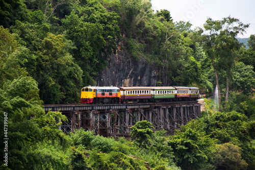 Train running on track between hellfire pass mountain and riverside Sai Yok waterfall and Khwae river bring thai people and foreign travelers travel visit at Tham krasae cave in Kanchanaburi, Thailand photo
