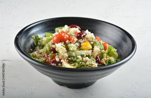 couscous healthy grain salad bowl with corn, bean, carrot and salad dressing sauce in white marble healthy poke bowl menu
