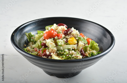couscous healthy grain salad bowl with corn, bean, carrot and salad dressing sauce in white marble healthy poke bowl menu