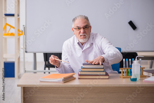 Old male chemist teacher in the classroom