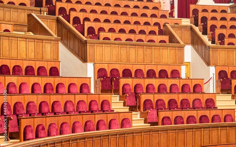 Full frame of empty chairs in an auditorium, conference room, parliament or theater. Empty comfortable red seats with numbers in cinema. 