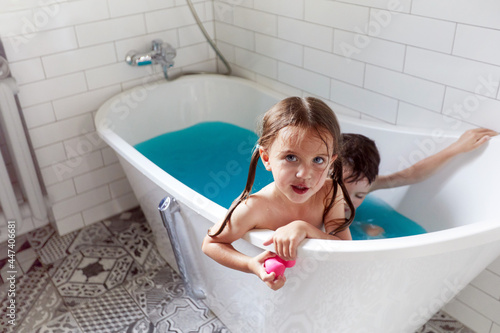 Vászonkép From above of adorable little brother and sister bathing in bathtub with blue wa