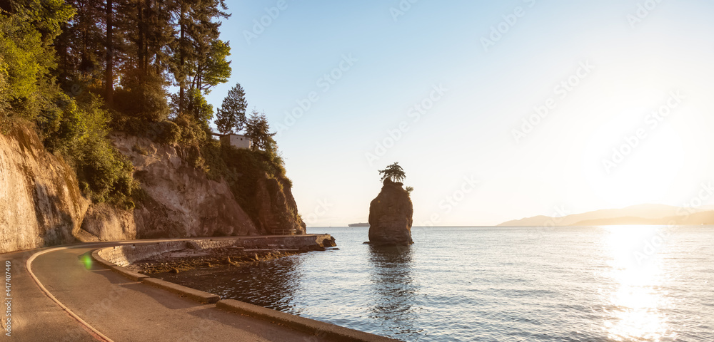 Fototapeta premium View of the Siwash Rock from Seawall at Stanley Park in a modern city. Downtown Vancouver, British Columbia, Canada. Sunny Summer Sunset.