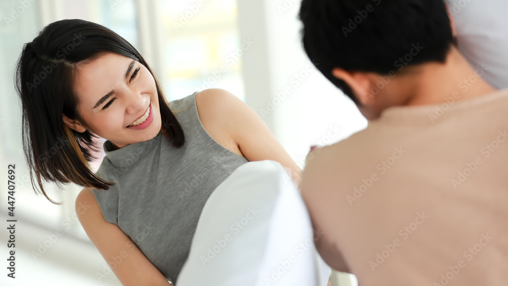 Funny shot of cute smiling young adult Asian woman in casual clothes having fun with a pillow fight with her husband in the foreground. Wife and husband playing spend time together in the morning Funny shot of cute smiling young adult Asian woman in casual clothes having fun with a pillow fight with her husband in the foreground. Wife and husband playing spend time together in the morning