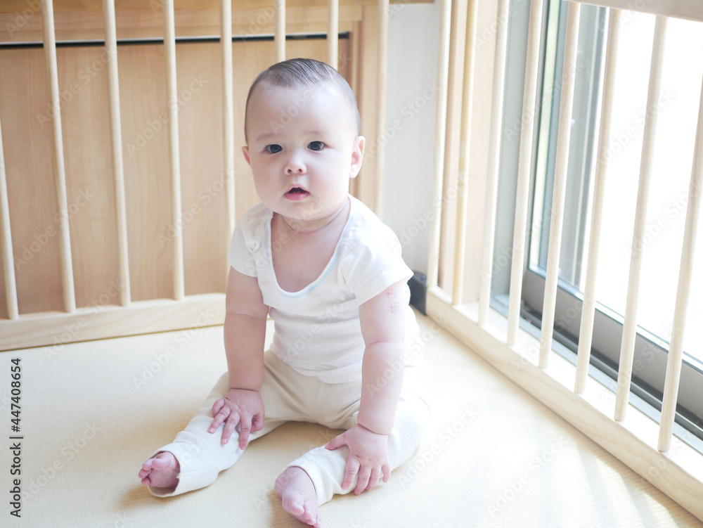 ベビーフェンスの中で座っているハーフの赤ちゃん ベビーフェンスの中で座っているハーフの赤ちゃん